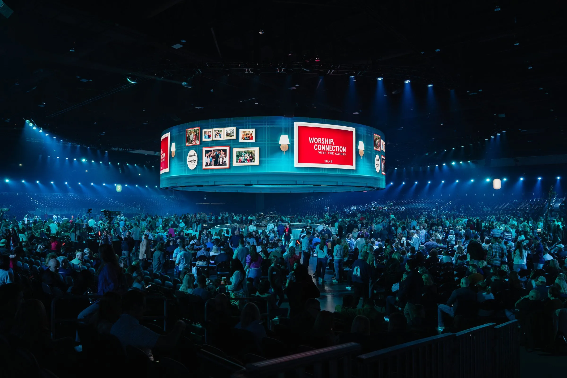 NEXT 2025 — wide arena view of the suspended 360° LED canopy lit blue with packed crowd below