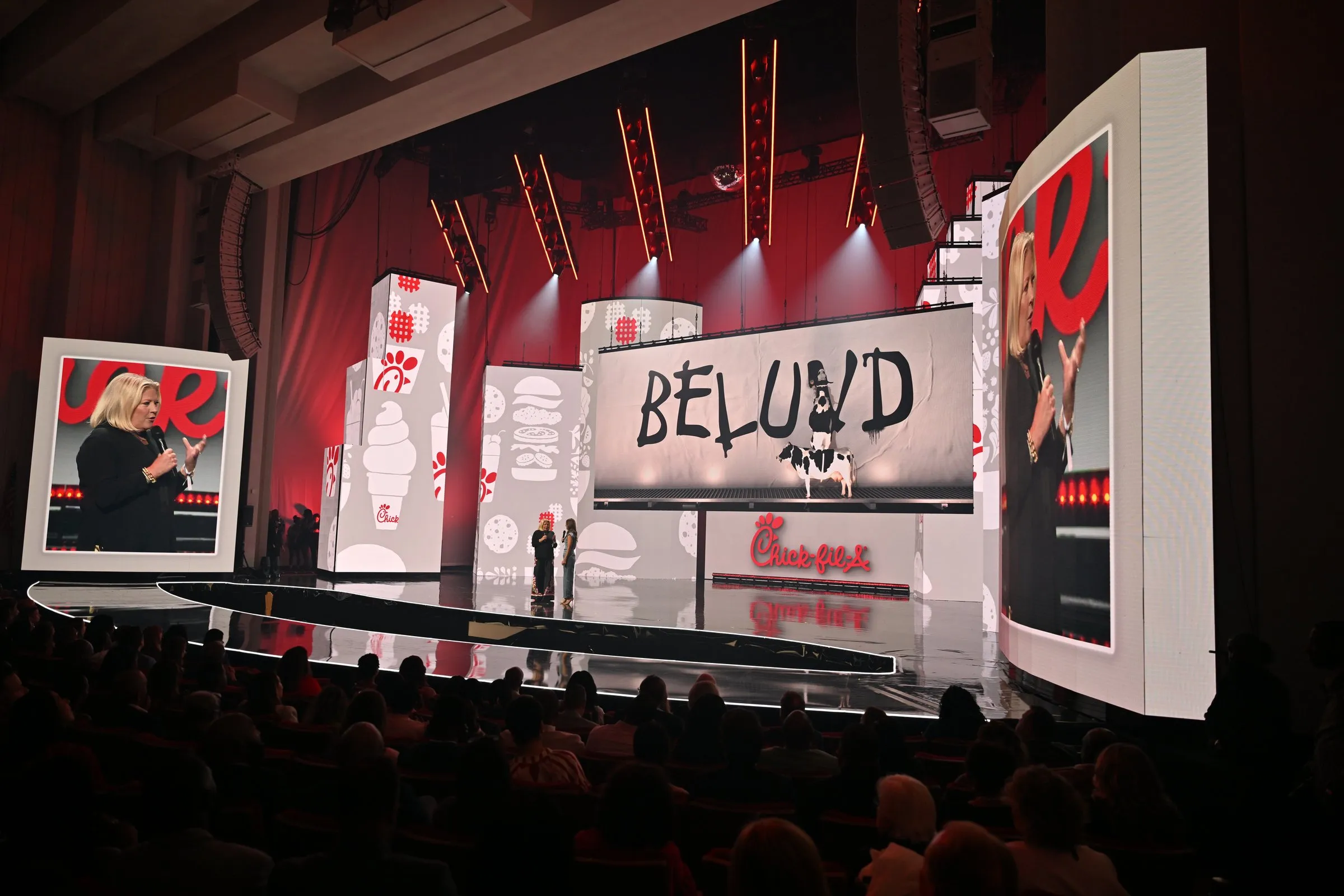 Beloved Benefit Chick-fil-A sponsor moment — "BELUVD" drippy logotype on the center LED with side IMAG of the host pair, Chick-fil-A logo present