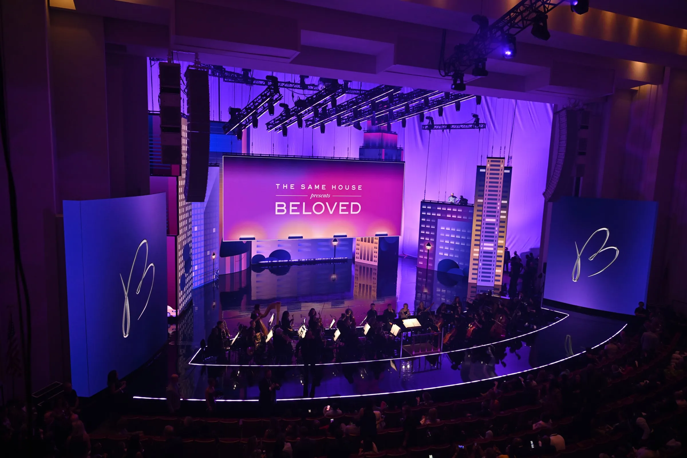 Beloved Benefit — "THE SAME HOUSE presents BELOVED" title card on a curved center LED with cityscape and B-mark wing screens