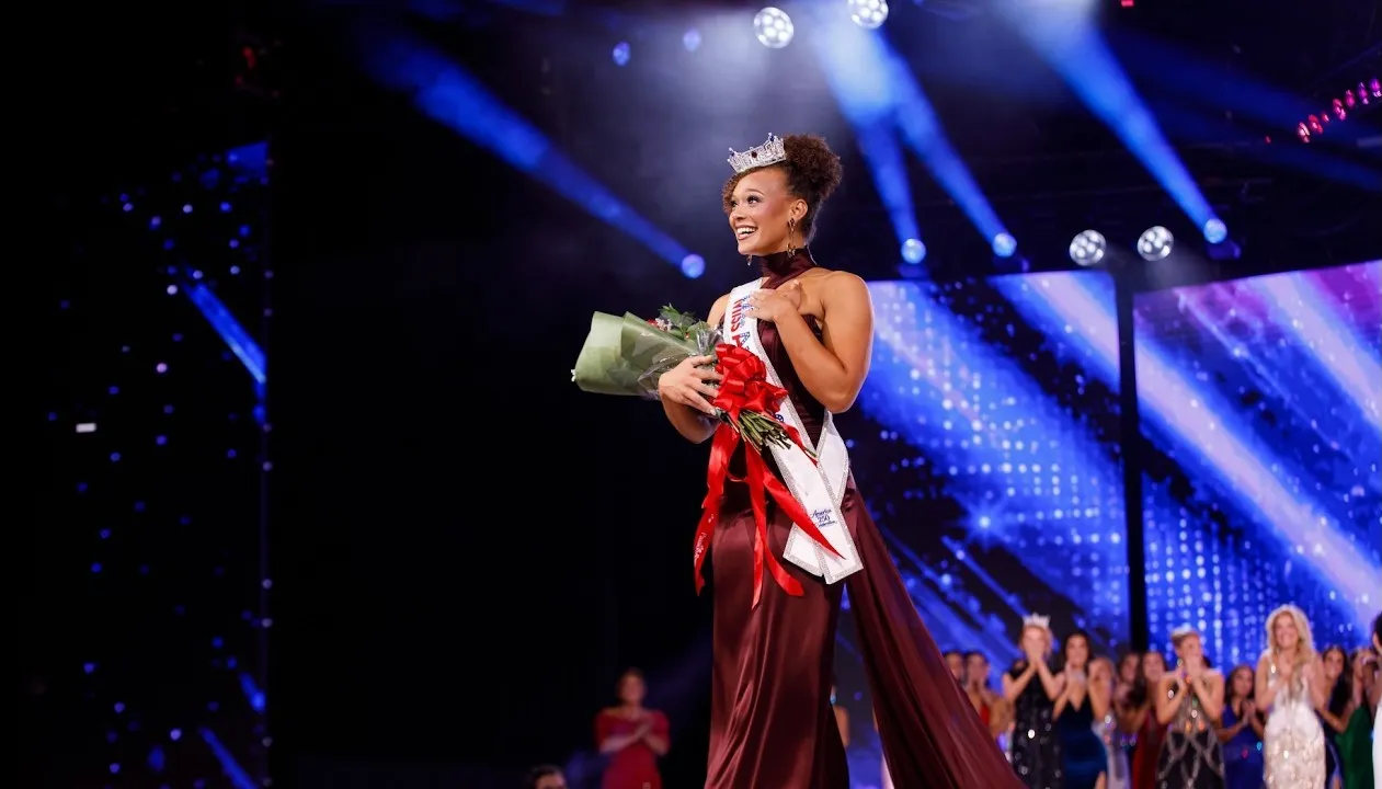 The newly crowned Miss America 2026 walks the stage as light streams run across the LED wall behind her