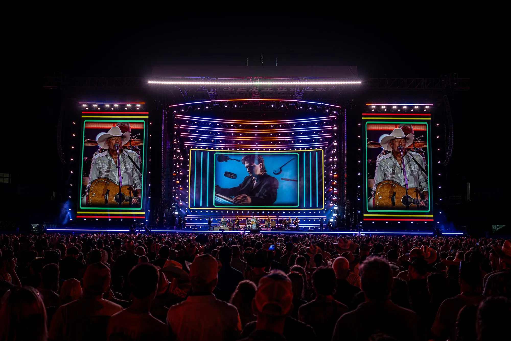 Retro neon frame treatment across all three stadium screens — archival Alan Jackson footage center, live IMAG on the sides