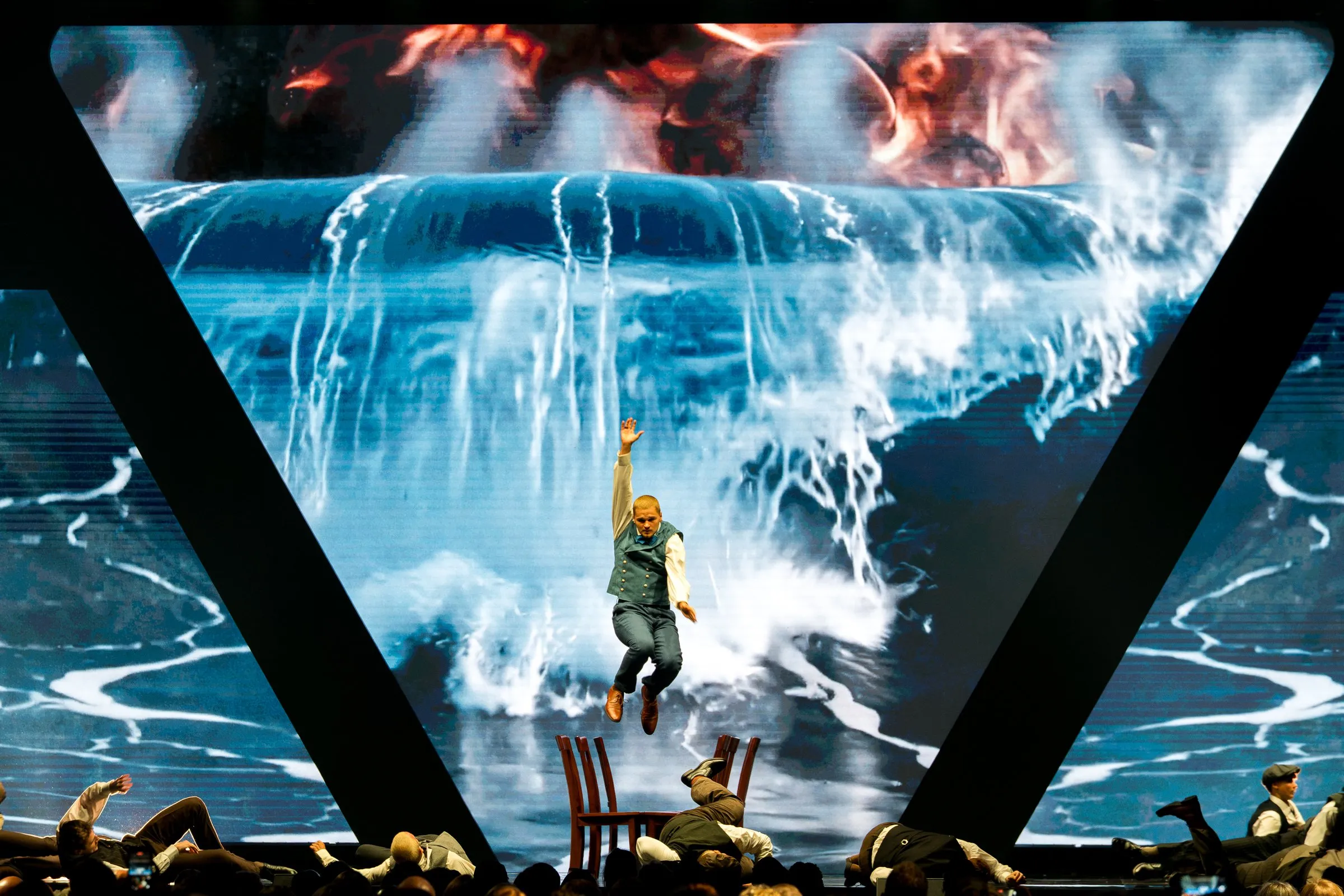 A dancer leaps in front of a crashing waterfall video look on the center LED during a musical performance