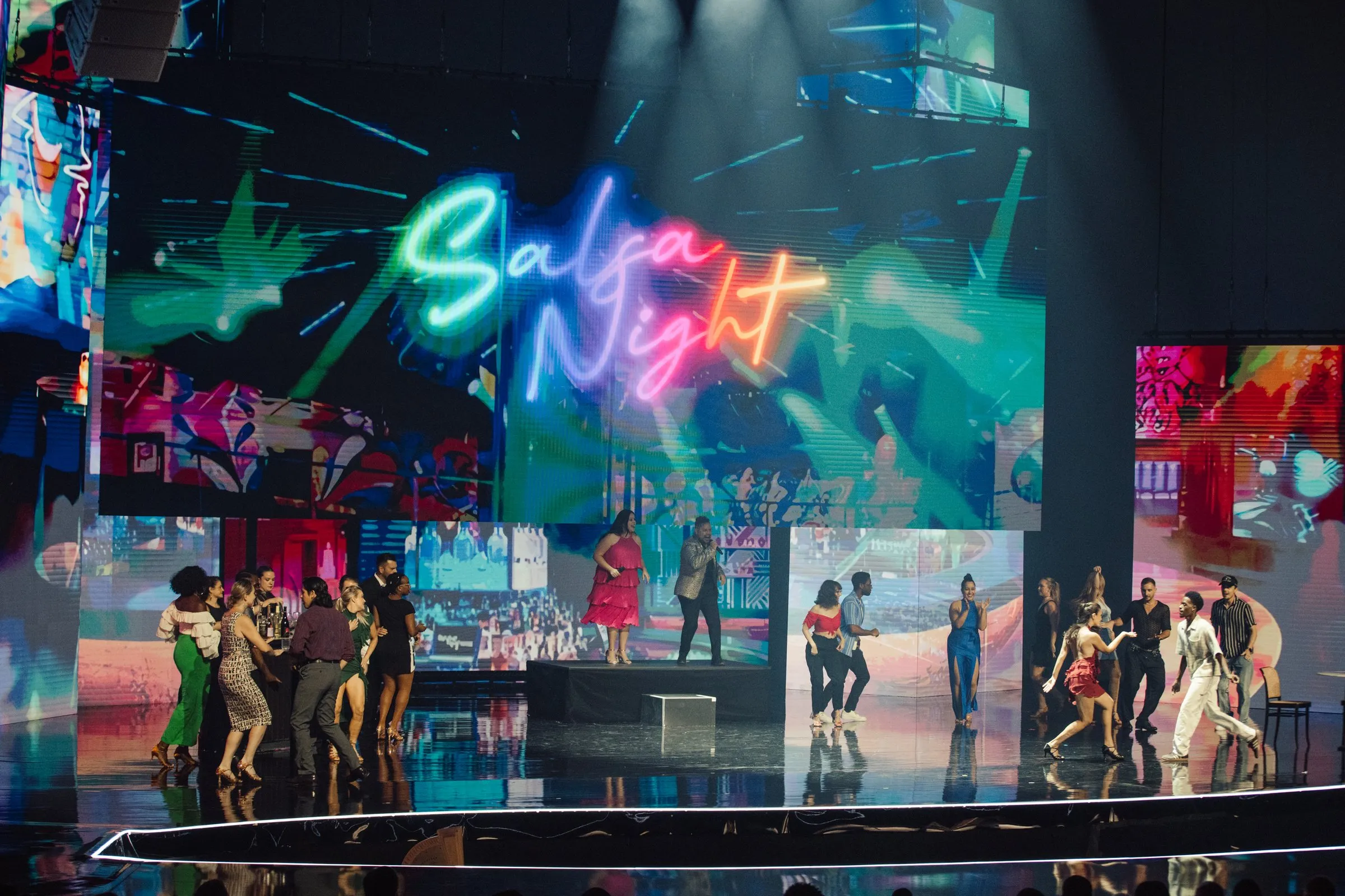 Beloved Benefit Salsa Night performance — neon "Salsa Night" sign on the main LED with dancers and audience filling the stage
