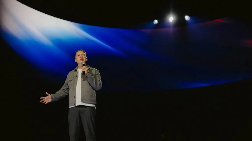 Beyond a Billion — speaker on stage in front of a sweeping abstract blue-and-red LED backdrop