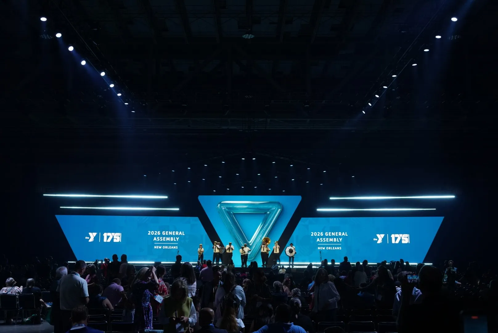 2026 General Assembly title look on the blue LED wings, with a glass Y triangle on the center screen and a brass band on stage